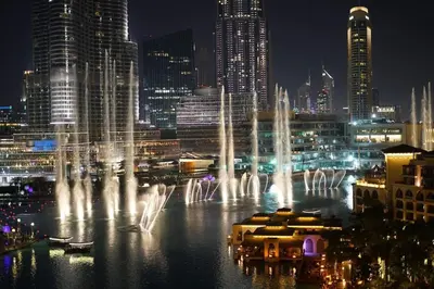 a group of water fountains in a city at night at Luxury in the Sky - 1BR Burj Inner Circle in Dubai