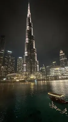 a boat in the water in front of a city at night at Luxury in the Sky - 1BR Burj Inner Circle in Dubai