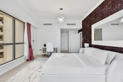 a bedroom with a white bed and a brick wall at Bright and Spacious 2BR with Pool and Gym Access in Dubai