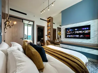 a bedroom with a white bed with a tv on the wall at Trophy-Brandnew Premium and Vibrant 1BR in JVC in Dubai