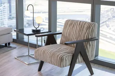 a chair in a room with a table and a lamp at Mahogany 4 - 2BR 6PAX - Panoramic Burj Khalifa View in Dubai