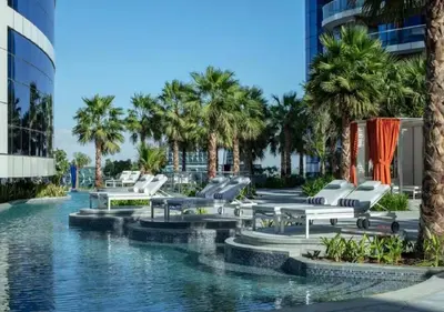 a resort pool with lounge chairs and palm trees at Mahogany 4 - 2BR 6PAX - Panoramic Burj Khalifa View in Dubai