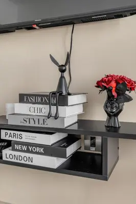 a shelf with a stack of books and a vase of flowers at Luxury new studio Dubai Marina 10min to the beach in Dubai