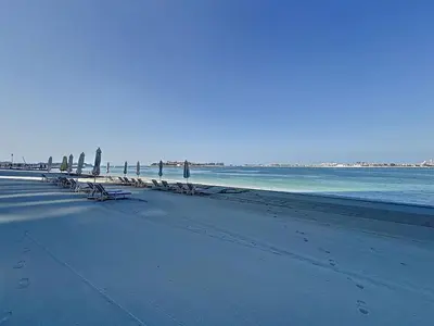 a beach with benches and umbrellas and the ocean at Grand Bleu - Luxurious One Bedroom with Sea View in Dubai