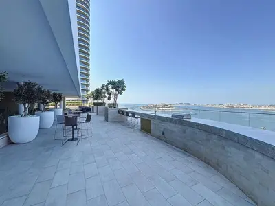 a balcony with chairs and tables and the ocean at Grand Bleu - Luxurious One Bedroom with Sea View in Dubai