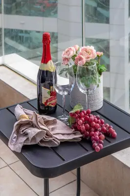 a table with two glasses and a bottle of wine and grapes at Frank Porter - Botanica Tower in Dubai