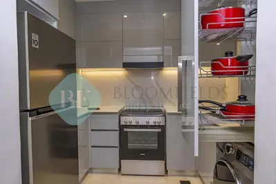 a kitchen with a stove and a refrigerator at Bloomfields Stylish 1Br In Binghatti Creek Jaddaf in Dubai