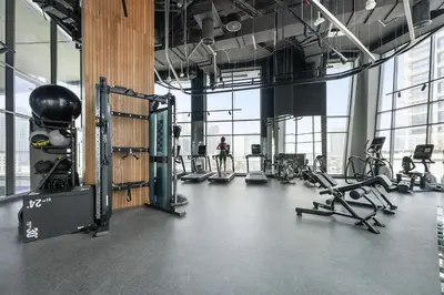 a gym with several tread machines and a person in the background at Silkhaus Highfloor 1BDR in 15 Northside Tower in Dubai