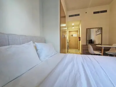 a white bed in a room with a table and chairs at Fully Furnished Modern Studio Apartment Nearby Meydan Racecourse in Dubai