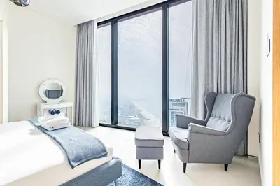 a bedroom with a bed and a chair and a window at High-Floor Luxury 2BR, Sea View, Address JBR in Dubai
