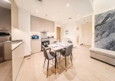 a kitchen and dining room with a table and chairs at Modern one bedroom apartment in lotus creek beach in Dubai