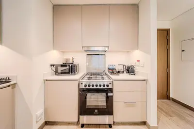 a kitchen with a stove and a microwave at Modern one bedroom apartment in lotus creek beach in Dubai