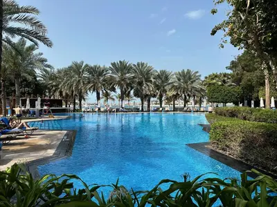 a large swimming pool with palm trees in the background at Dream Palm Residence 3BR Luxury Apartment on Palm Jumeirah in Dubai