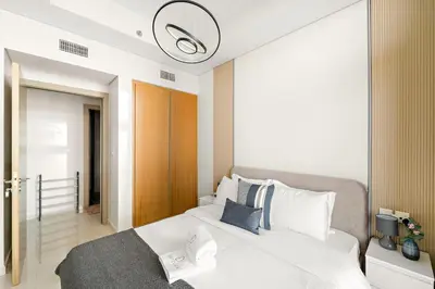 a bedroom with a large white bed with a light at FIRST CLASS 1BR Luxe Comfort Stylish Design in Dubai