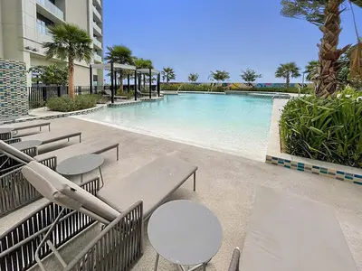 a swimming pool with tables and chairs next to a building at FIRST CLASS 1BR Luxe Comfort Stylish Design in Dubai