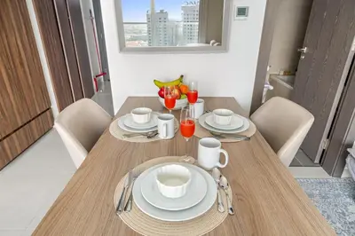 a wooden table with plates and cups and drinks on it at FIRST CLASS Studio Cozy Luxe Sanctuary in Dubai