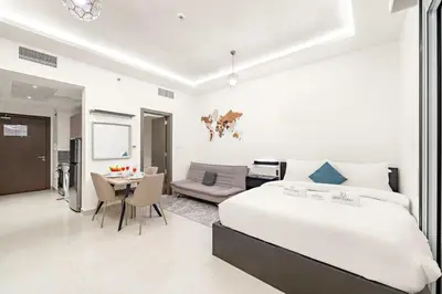 a white bedroom with a bed and a dining room at FIRST CLASS Studio Cozy Luxe Sanctuary in Dubai
