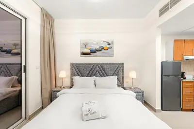 a bedroom with a white bed and a refrigerator at FIRST CLASS Studio Cozy & Chic Retreat in Dubai