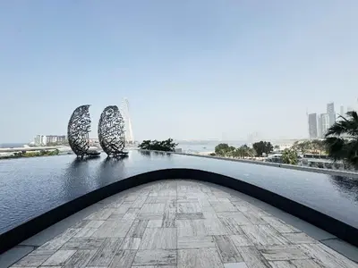 a bridge over a body of water with two sculptures at PRIVACASA - The Address Beach Resort residences in Dubai