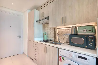 a small kitchen with a sink and a microwave at The Seven Palm with free rooftop pool & beach in Dubai
