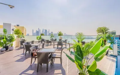 a patio with tables and chairs on the roof of a building at The Seven Palm with free rooftop pool & beach in Dubai