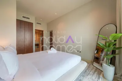 a bedroom with a white bed and a mirror at Spacious and Elegant 2BR Marina Gate 2 in Dubai