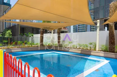 a swimming pool with a large umbrella and chairs at Spacious and Elegant 2BR Marina Gate 2 in Dubai