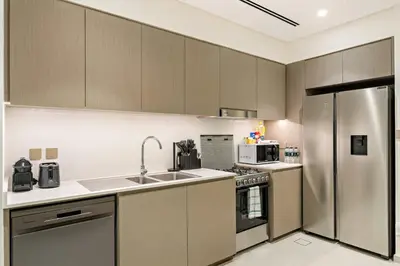 a kitchen with a stainless steel refrigerator and appliances at Panoramic 2BR with Pool & Burj View Next to Mall in Dubai