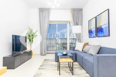 a living room with a blue couch and a tv at Bloomfields Stylish 1br Orchid Residence in Dubai