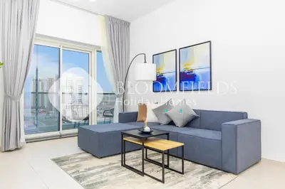 a living room with a blue couch and a table at Bloomfields Stylish 1br Orchid Residence in Dubai