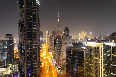 a city lit up at night with tall buildings at 4BHK in Business Bay w Burj Khalifa View Noora 4304 in Dubai
