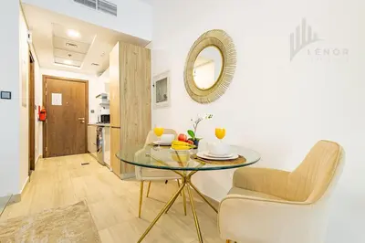 a dining room with a glass table and a mirror at Chic Studio Living JVC in Dubai