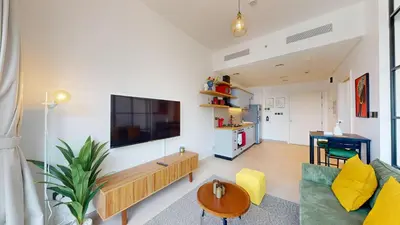 a living room with a couch and a tv on a wall at Cozy and Modern 1BR in Dubai Hills in Dubai