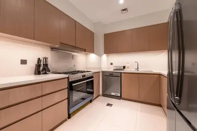 a kitchen with wooden cabinets and a stainless steel refrigerator at Luxury 4BR with Hermes Touch & Burj Khalifa View in Dubai
