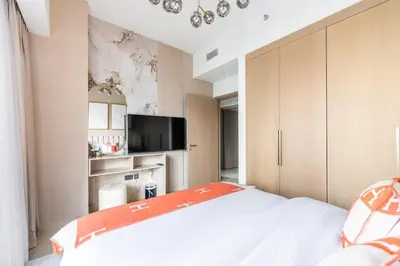 a bedroom with a large white bed with an orange blanket at Luxury 4BR with Hermes Touch & Burj Khalifa View in Dubai