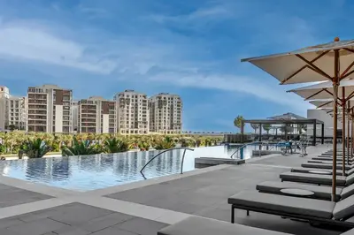 a pool with chairs and an umbrella and buildings at Palace residence creek harbour in Dubai