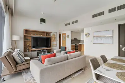a living room with a couch and a tv at Elegant Creekside 1BR with Panoramic Views in Dubai