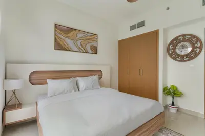a bedroom with a white bed and a cabinet at Elegant Creekside 1BR with Panoramic Views in Dubai