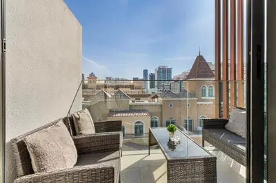 a balcony with wicker furniture and a view of a city at Waves - Elegant & Lavish Studio Apt for 4 in JVC in Dubai