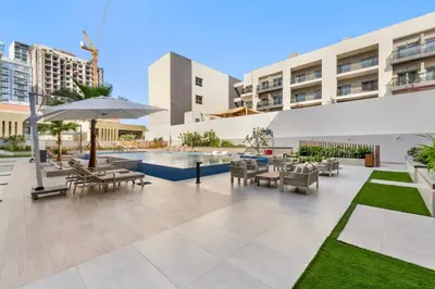 an outdoor patio with tables and chairs and an umbrella at Waves - Elegant & Lavish Studio Apt for 4 in JVC in Dubai
