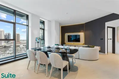 a dining room and living room with a table and chairs at Luxe 2 Bedroom with Burj Khalifa and Canal Views in Dubai