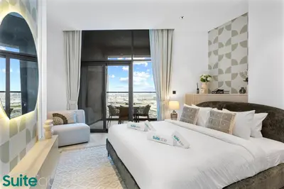 a bedroom with a large white bed and a living room at Luxe 2 Bedroom with Burj Khalifa and Canal Views in Dubai