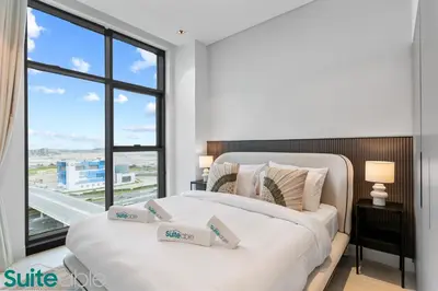 two beds in a bedroom with a large window at Luxe 2 Bedroom with Burj Khalifa and Canal Views in Dubai