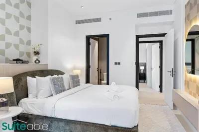 a bedroom with a large white bed and a hallway at Luxe 2 Bedroom with Burj Khalifa and Canal Views in Dubai