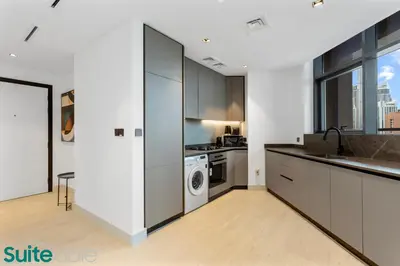 a kitchen with white cabinets and a washer and dryer at Luxe 2 Bedroom with Burj Khalifa and Canal Views in Dubai