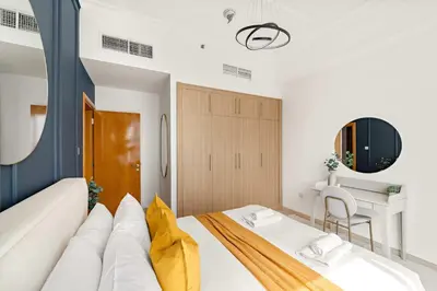 a bedroom with a white bed and a desk at Silkhaus Homey 2BR at Mayfair Tower in Business Bay in Dubai