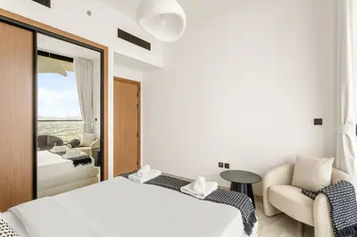 a bedroom with a bed and a chair and a mirror at VayK - Luxury 2BR with Jacuzzi in JVC in Dubai