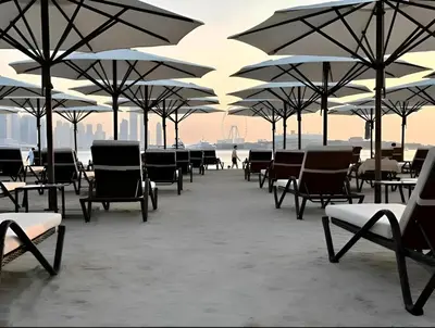 a group of tables and chairs with umbrellas at Dubai Palm Jumeirah - Free Infiniti Pool and Private Beach in Dubai
