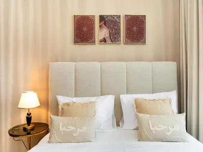 a bedroom with a white bed with two pictures on the wall at Burj Khalifa View Luxury Apt - 7 min to Dubai Mall in Dubai