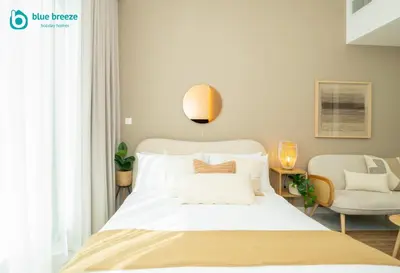 a bedroom with a white bed and a chair at Blue Breeze - Elegant Studio in Serenity Lake 5, JVC in Dubai